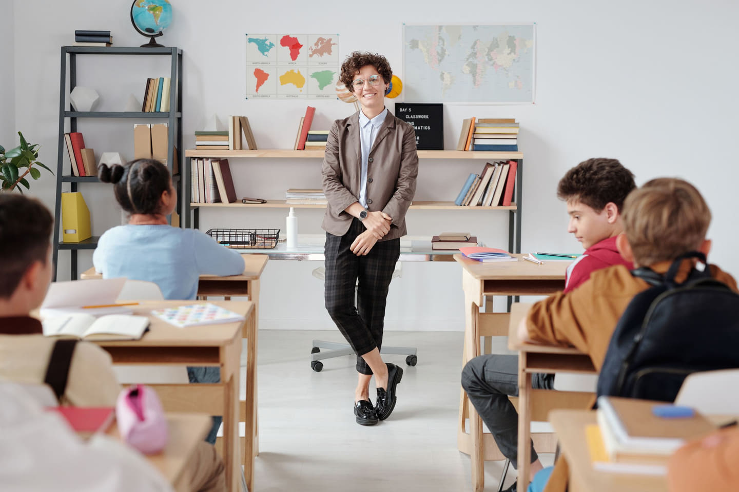 A teacher standing at the front of a classroom with students at their desks
